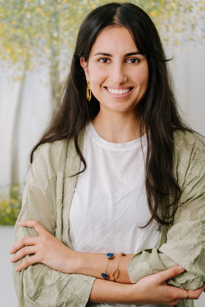Samaneh smiling, arms folded, in a sage embroidered jacket