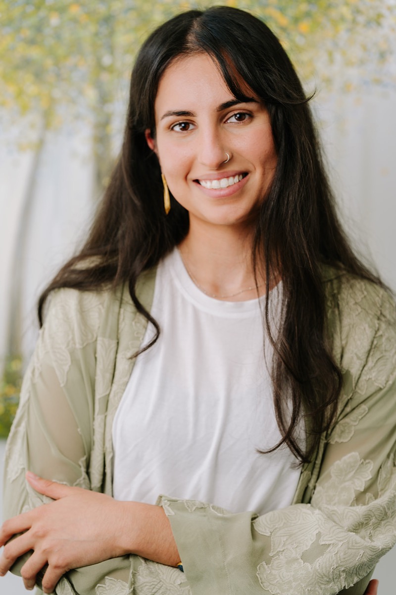 Samaneh smiling, in a sage embroidered jacket over a white tee